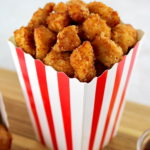 closeup of Keto Popcorn Chicken in popcorn container sitting on cutting board