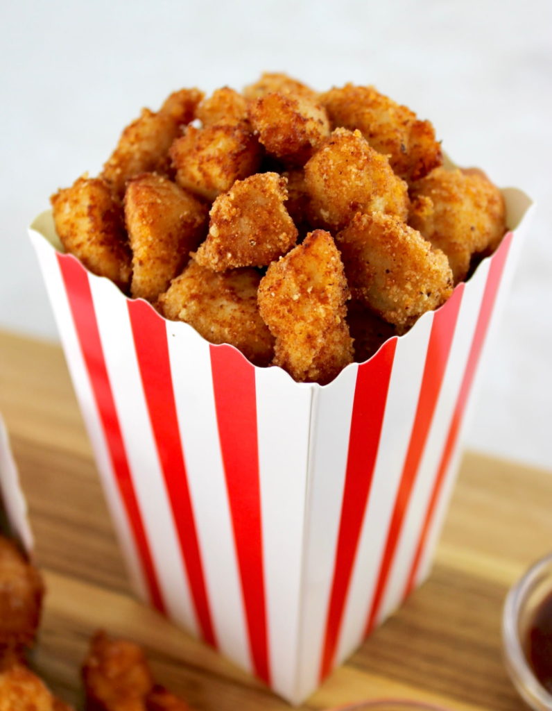 closeup of Keto Popcorn Chicken in popcorn container sitting on cutting board