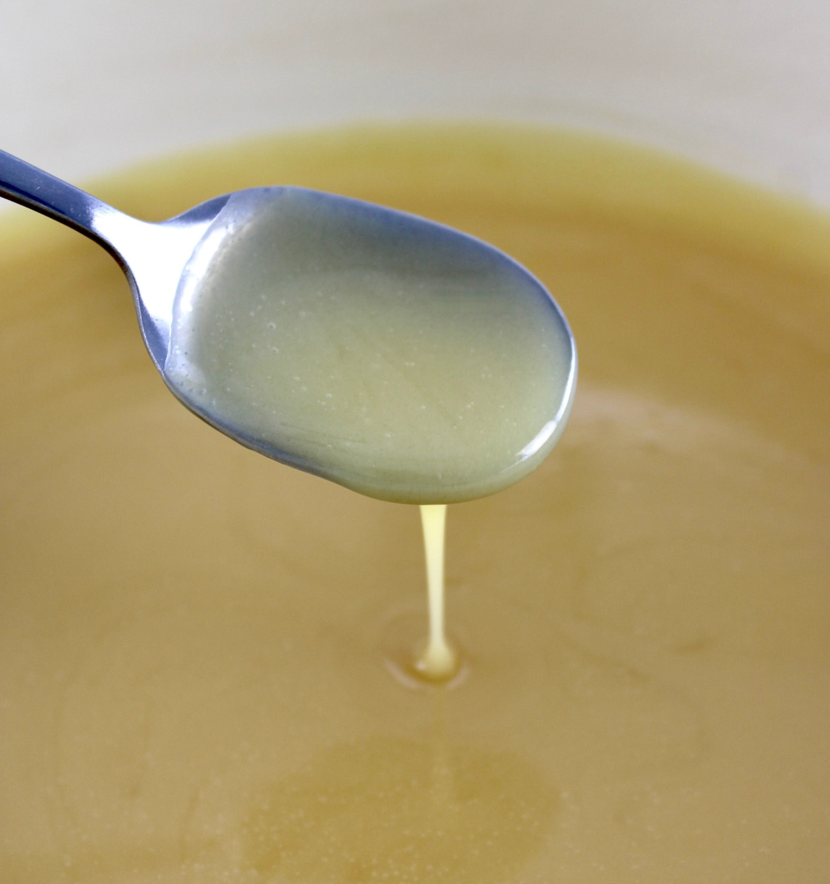 keto sweetened condensed milk in skillet with spoon dripping some