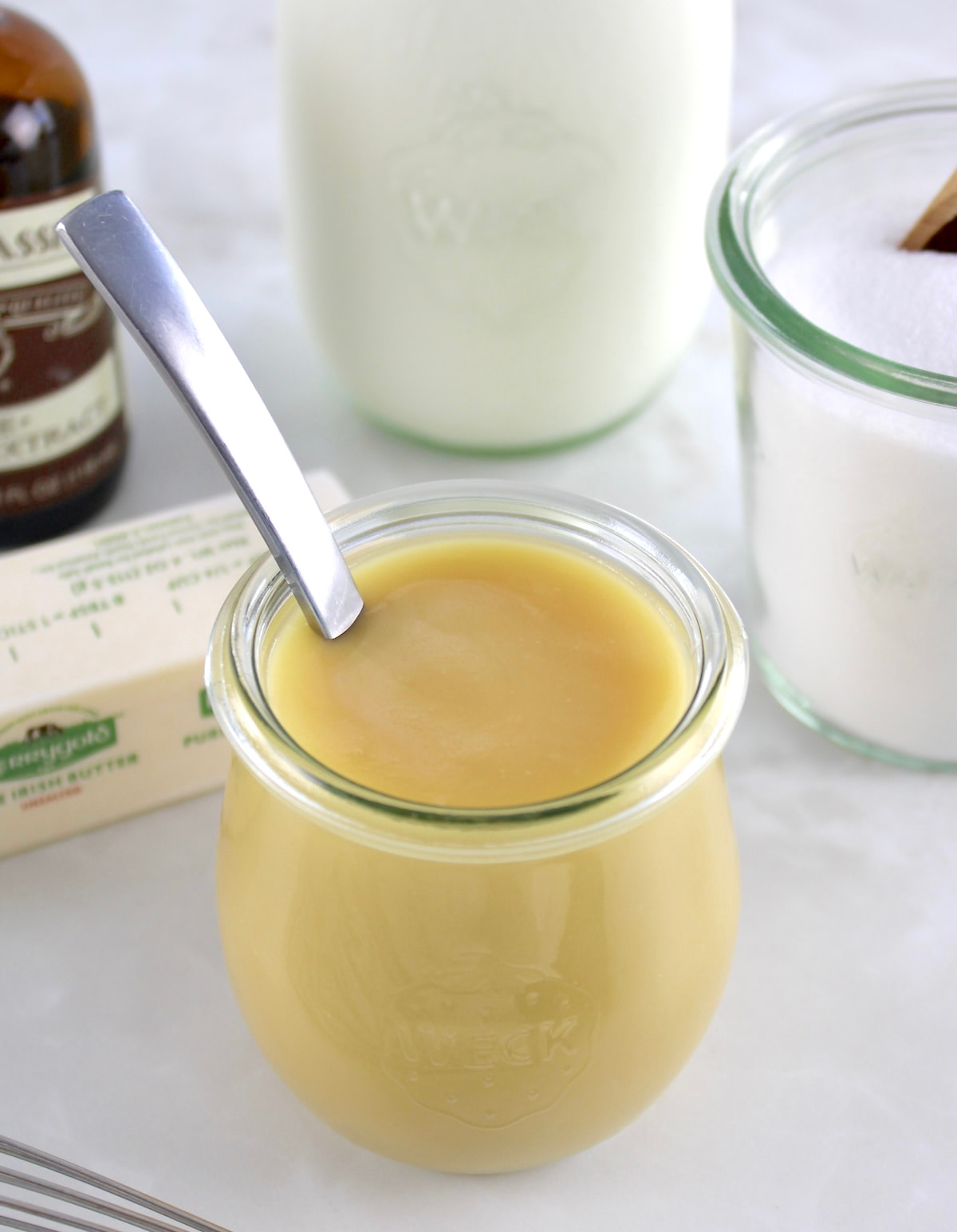 Keto Sweetened Condensed Milk in an open jar with spoon sticking up