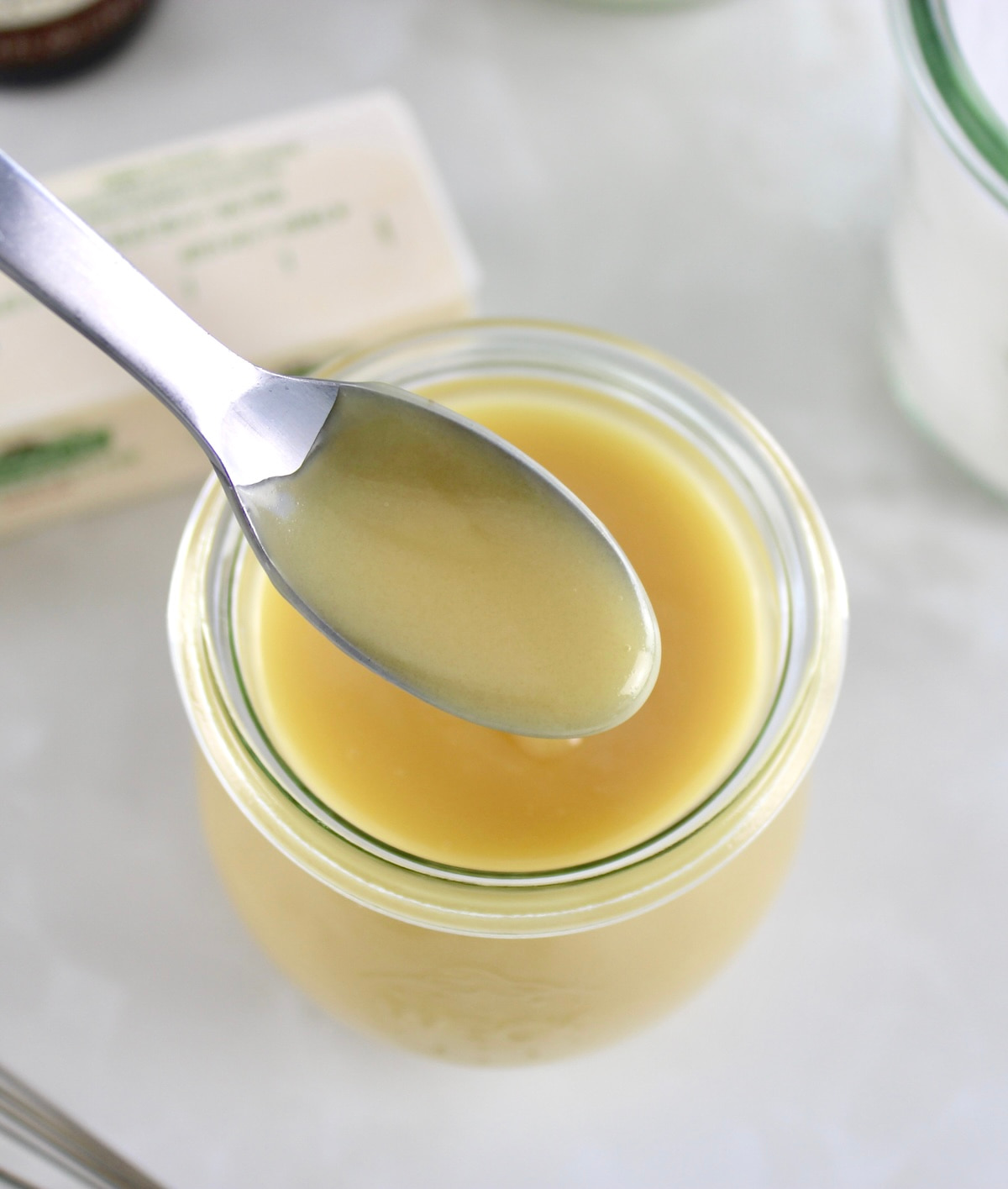 overhead view of Keto Sweetened Condensed Milk in spoon held up over jar