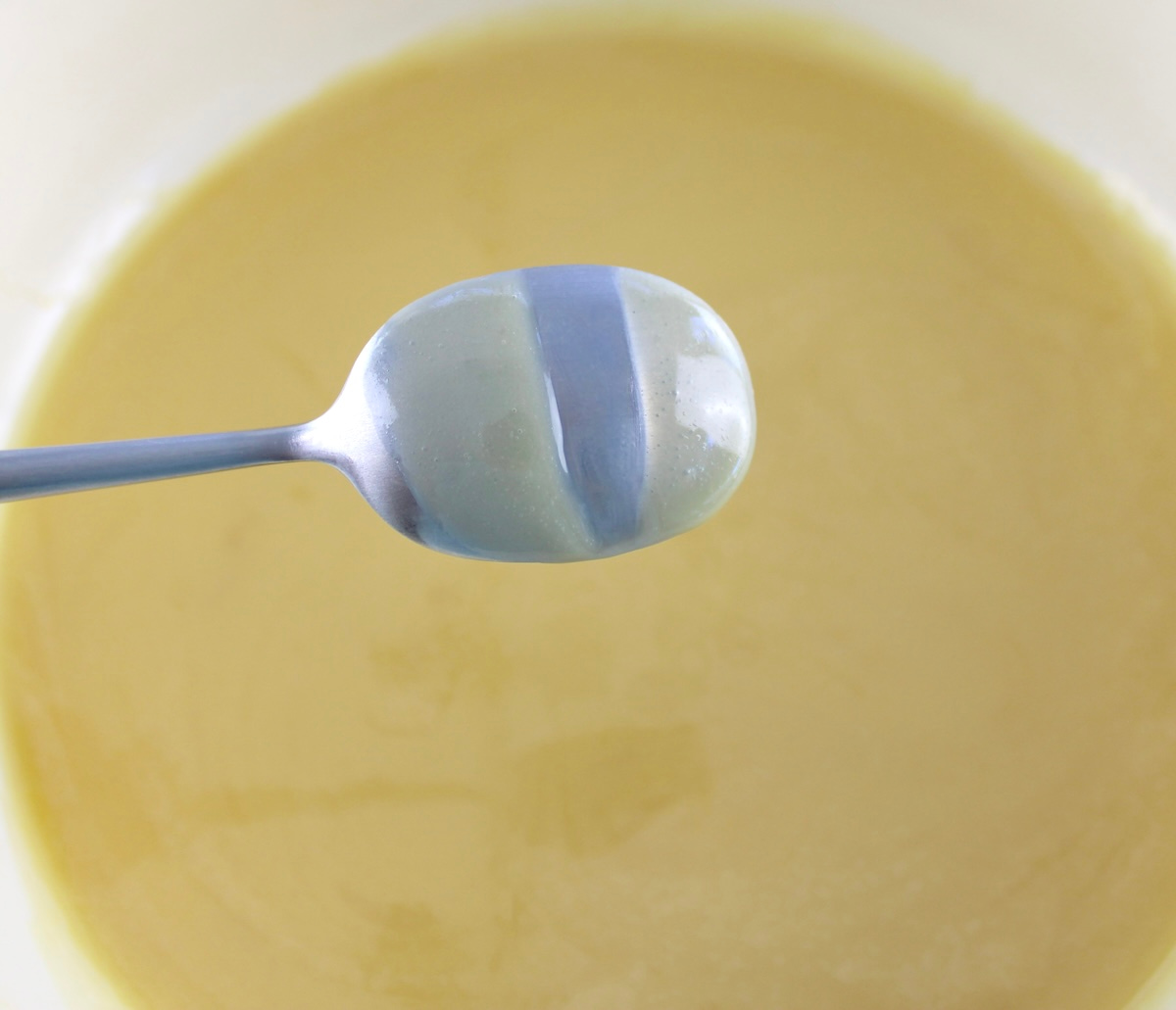 Keto Sweetened Condensed Milk on back of spoon with line through it