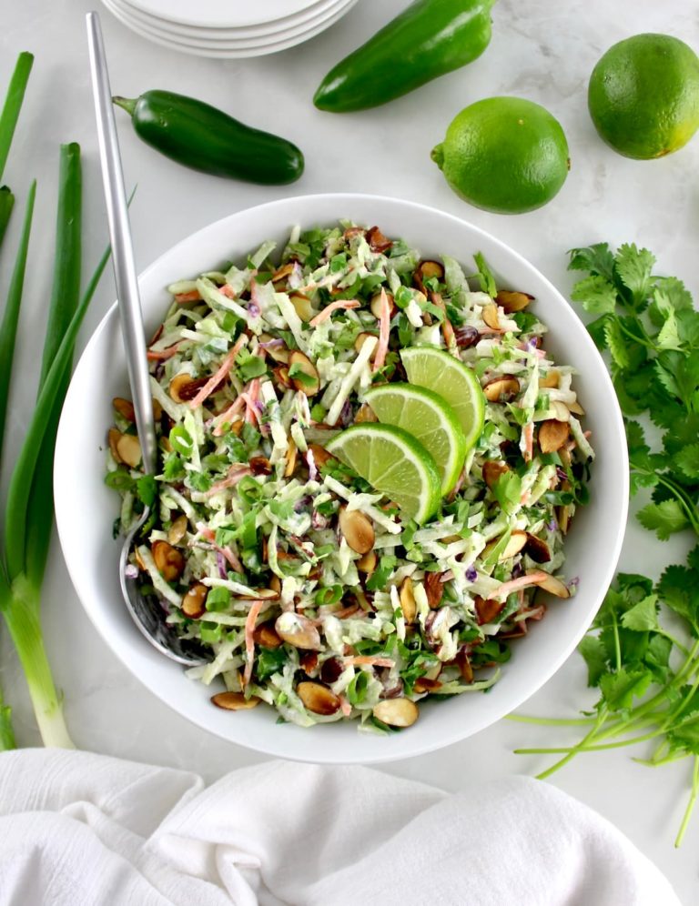 overhead view of Lime Cilantro Broccoli Slaw in white bowl with silver serving spoon on side