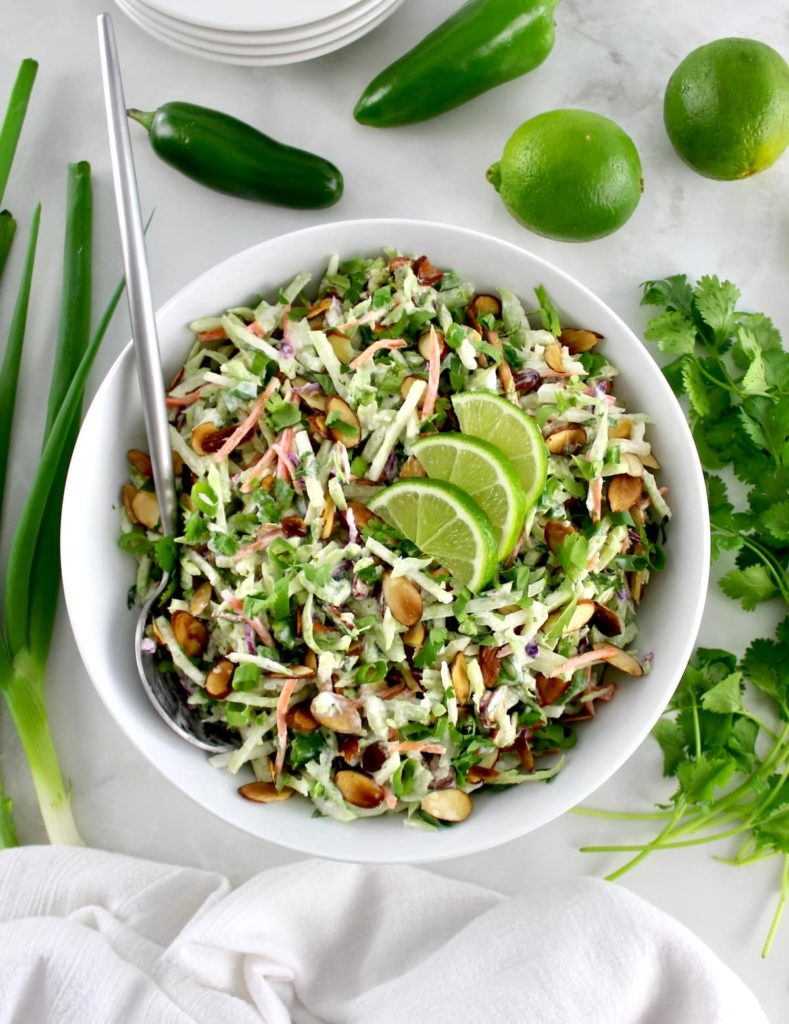 overhead view of Lime Cilantro Broccoli Slaw in white bowl with silver serving spoon on side