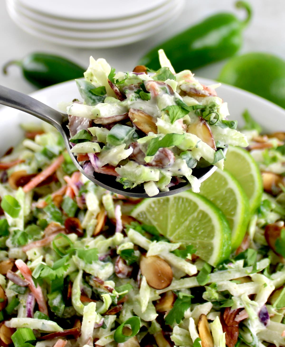 Lime Cilantro Broccoli Slaw in silver serving spoon over white bowl
