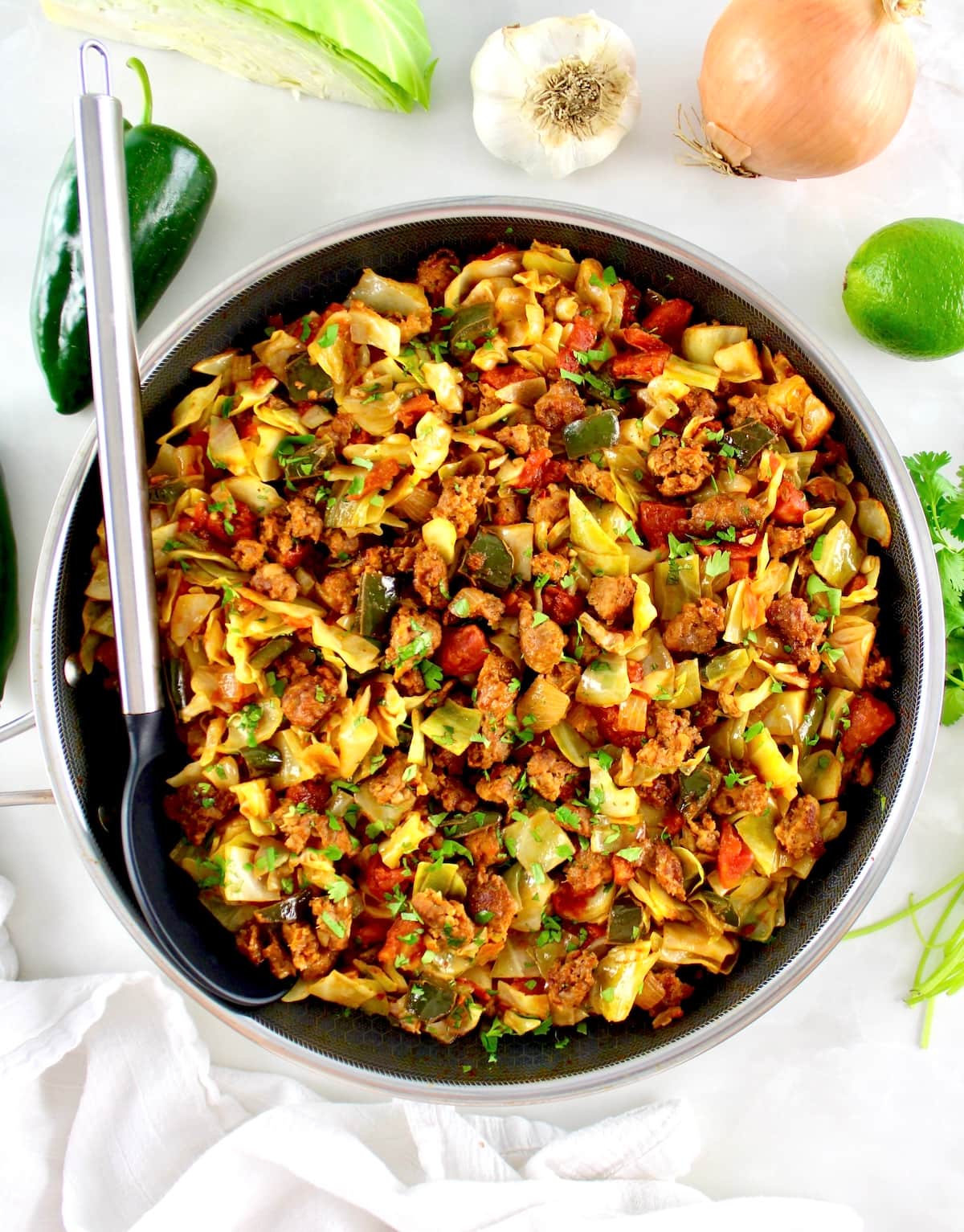 overhead view of Mexican Chorizo and Cabbage in skillet with serving spoon on side