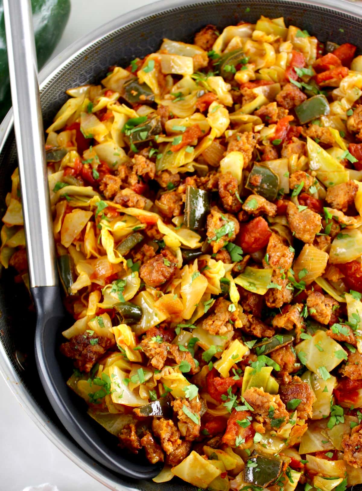 closeup of Mexican Chorizo and Cabbage in skillet with black serving spoon on side