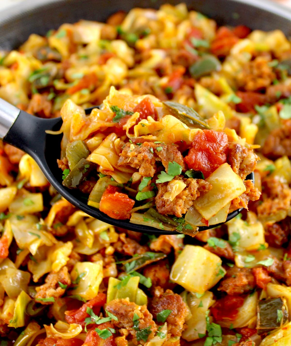 closeup of Mexican Chorizo and Cabbage in serving spoon held up over skillet
