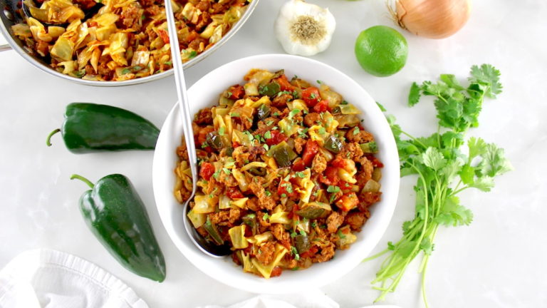 overhead view of Mexican Chorizo and Cabbage in white bowl with silver serving spoon on side