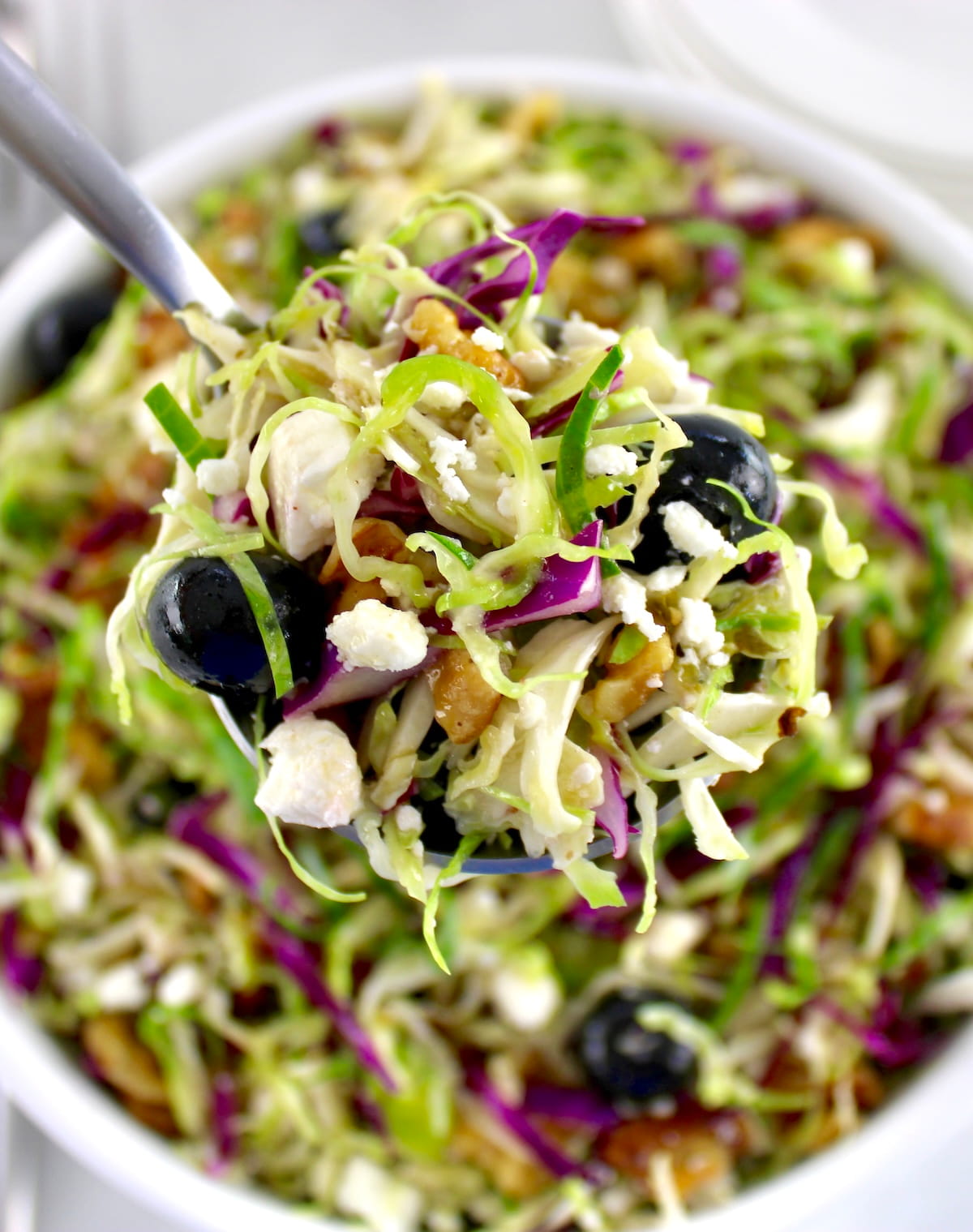 spoonful of Shaved Brussels Sprouts Salad held up over white bowl