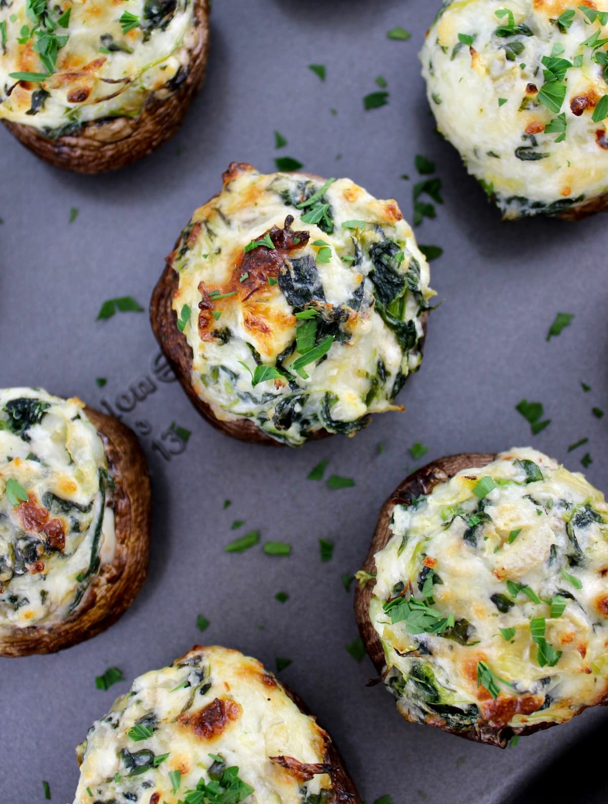 overhead view of Spinach Artichoke Stuffed Mushrooms on baking sheet with chopped parsley