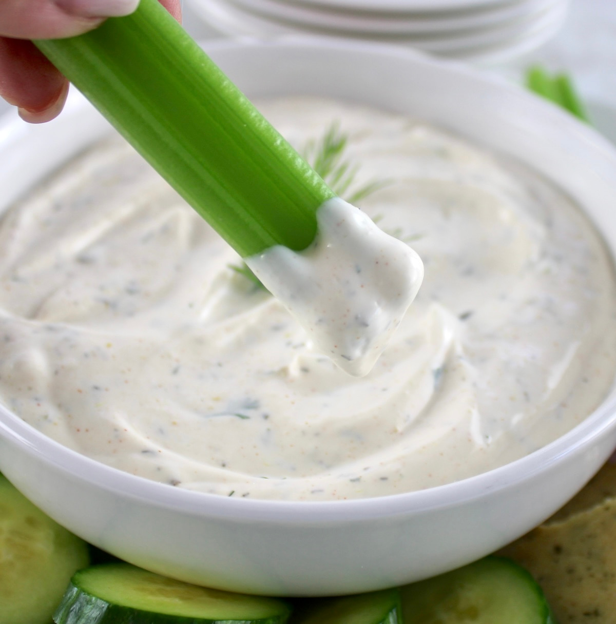 holding celery that was dipped in Easy Veggie Dip in white bowl