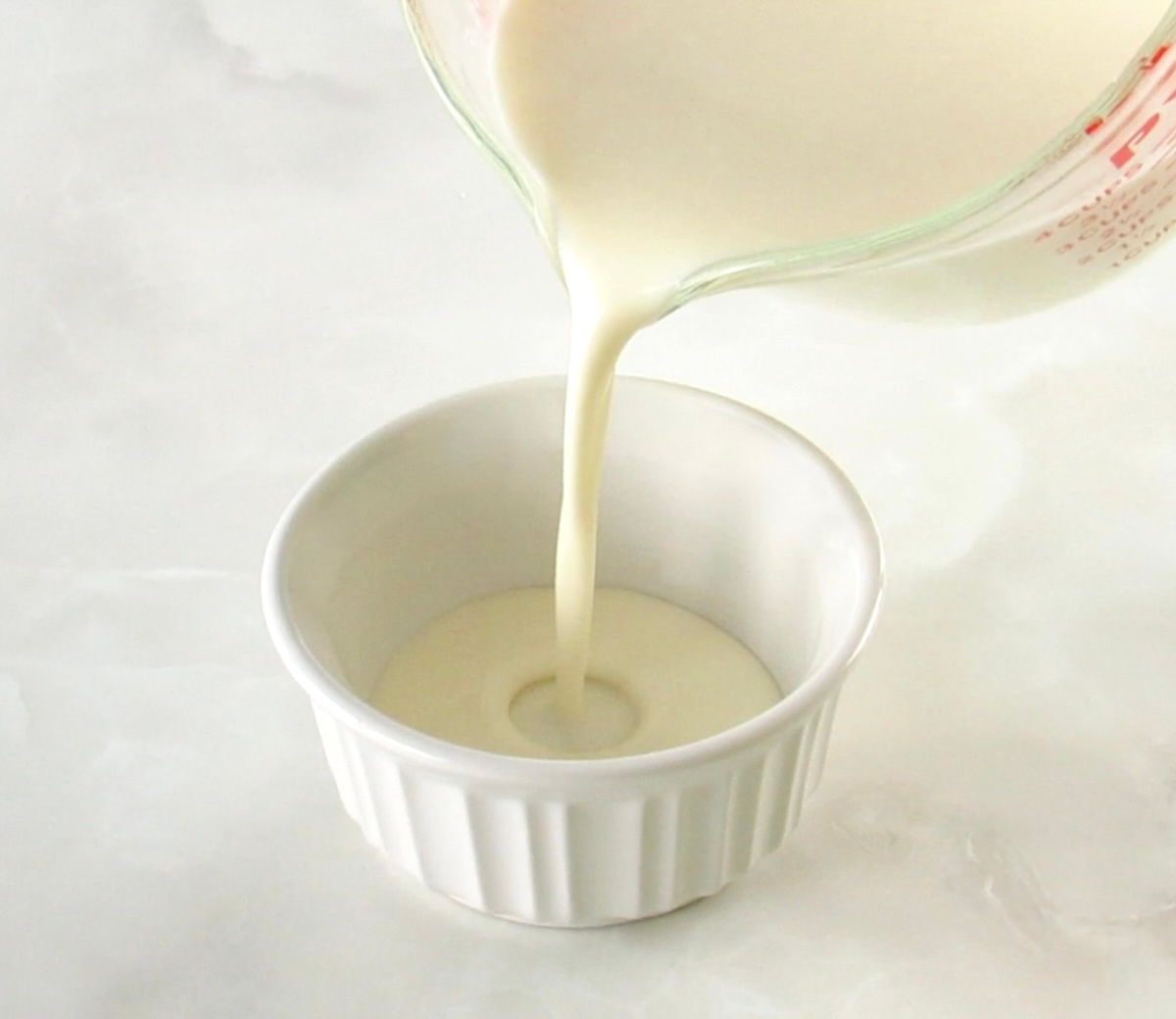 pouring Keto Panna Cotta mix into white ramekin