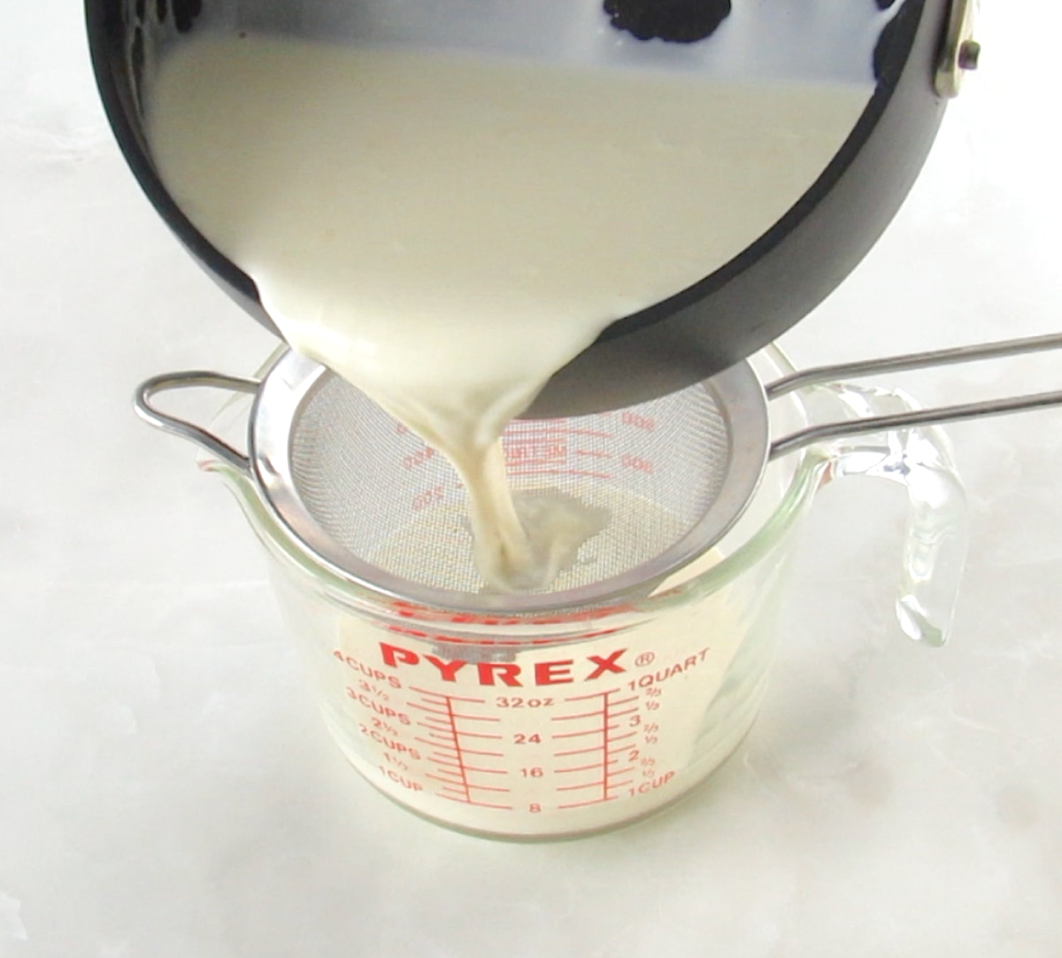 straining Keto Panna Cotta mix throw sieve into measuring cup