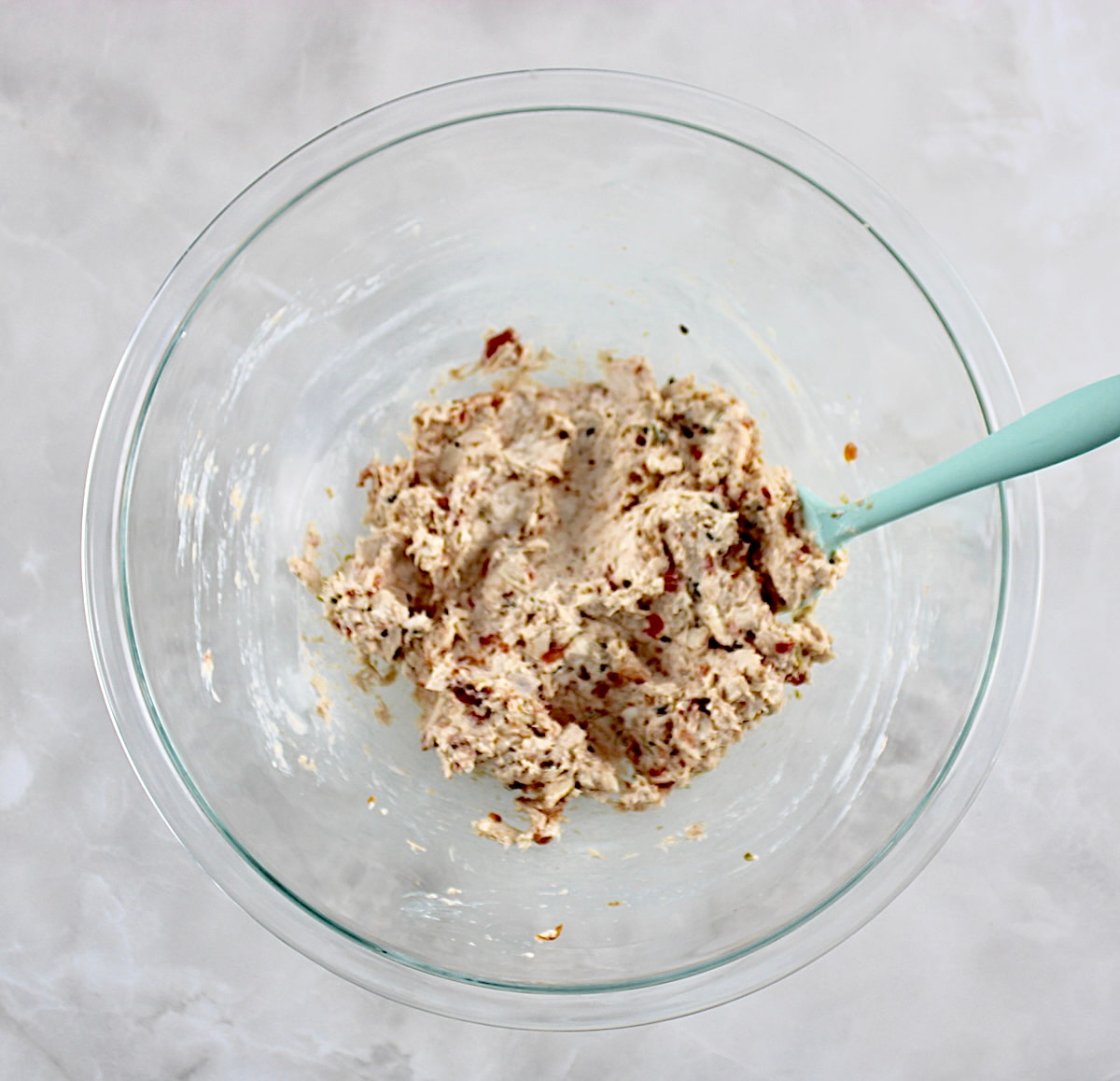 Mini Chicken Taquitos filling in glass bowl with blue spoon