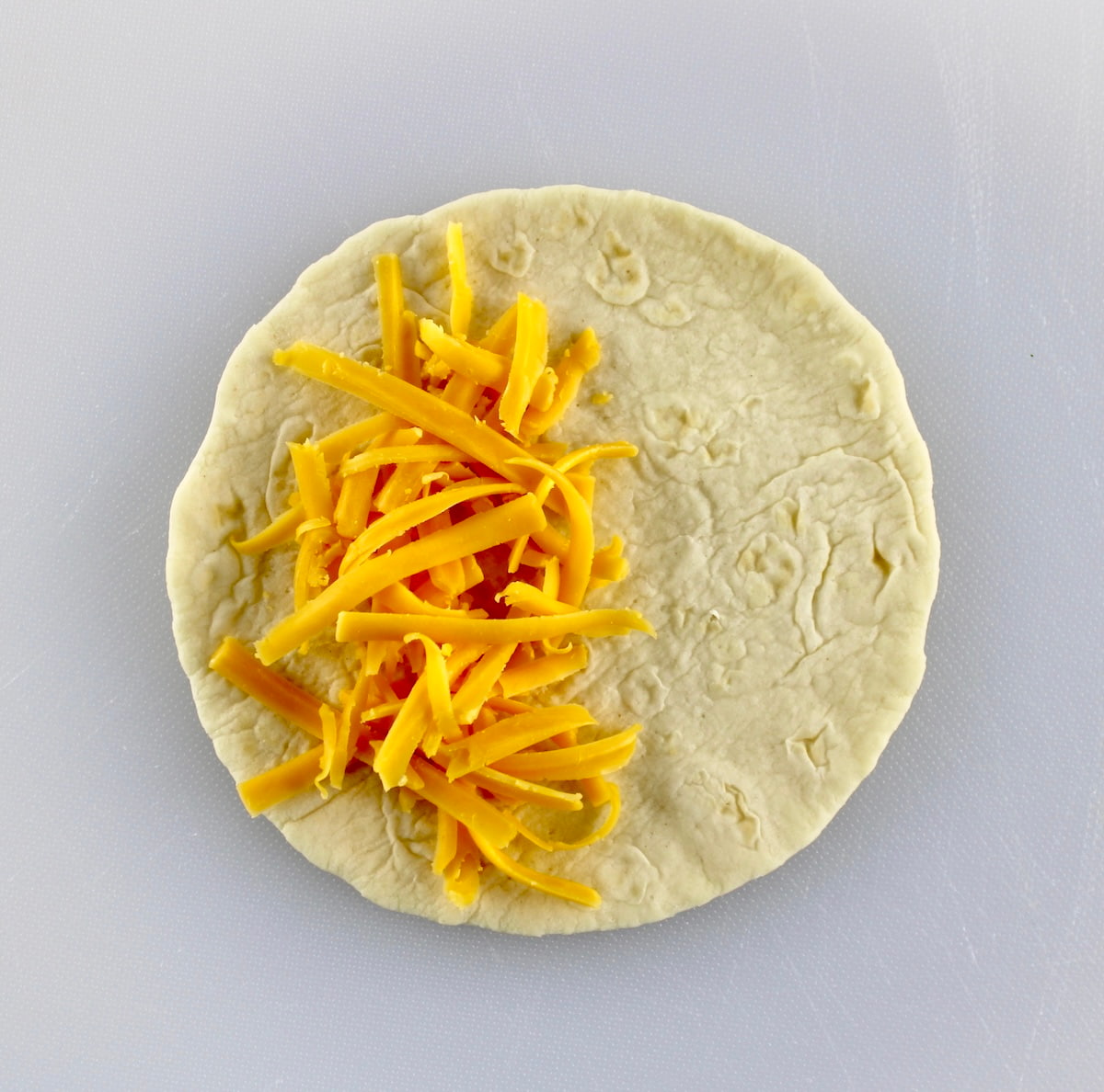 tortilla with shredded cheddar on half