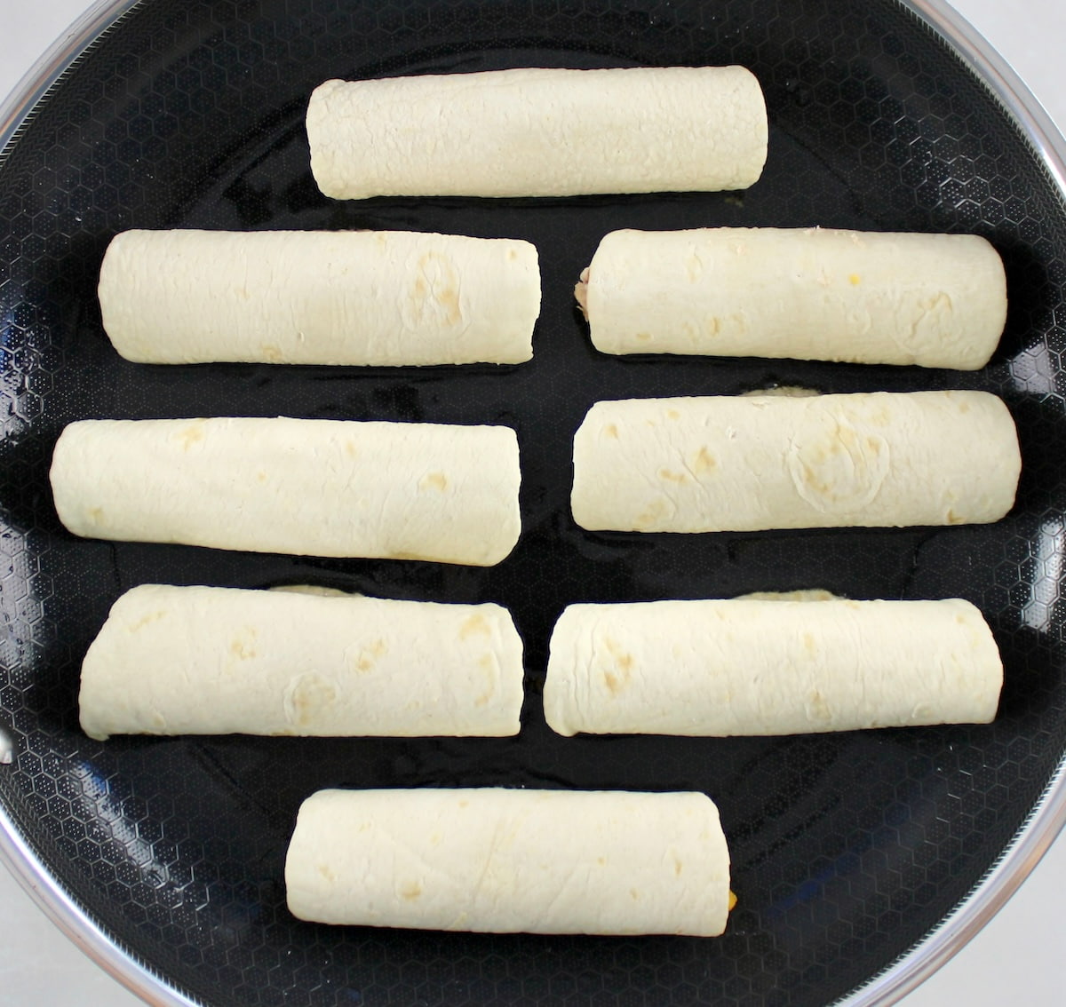 8 Mini Chicken Taquitos frying in skillet