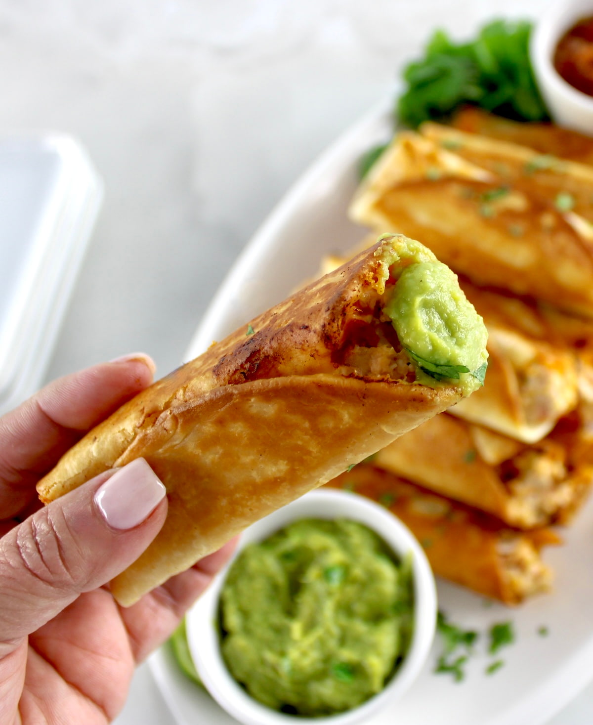 holding up Mini Chicken Taquito dipped in guacamole