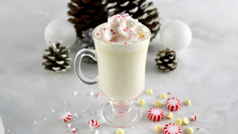 closeup side view of Peppermint White Hot Chocolate in glass with whip cream and crush mints on top