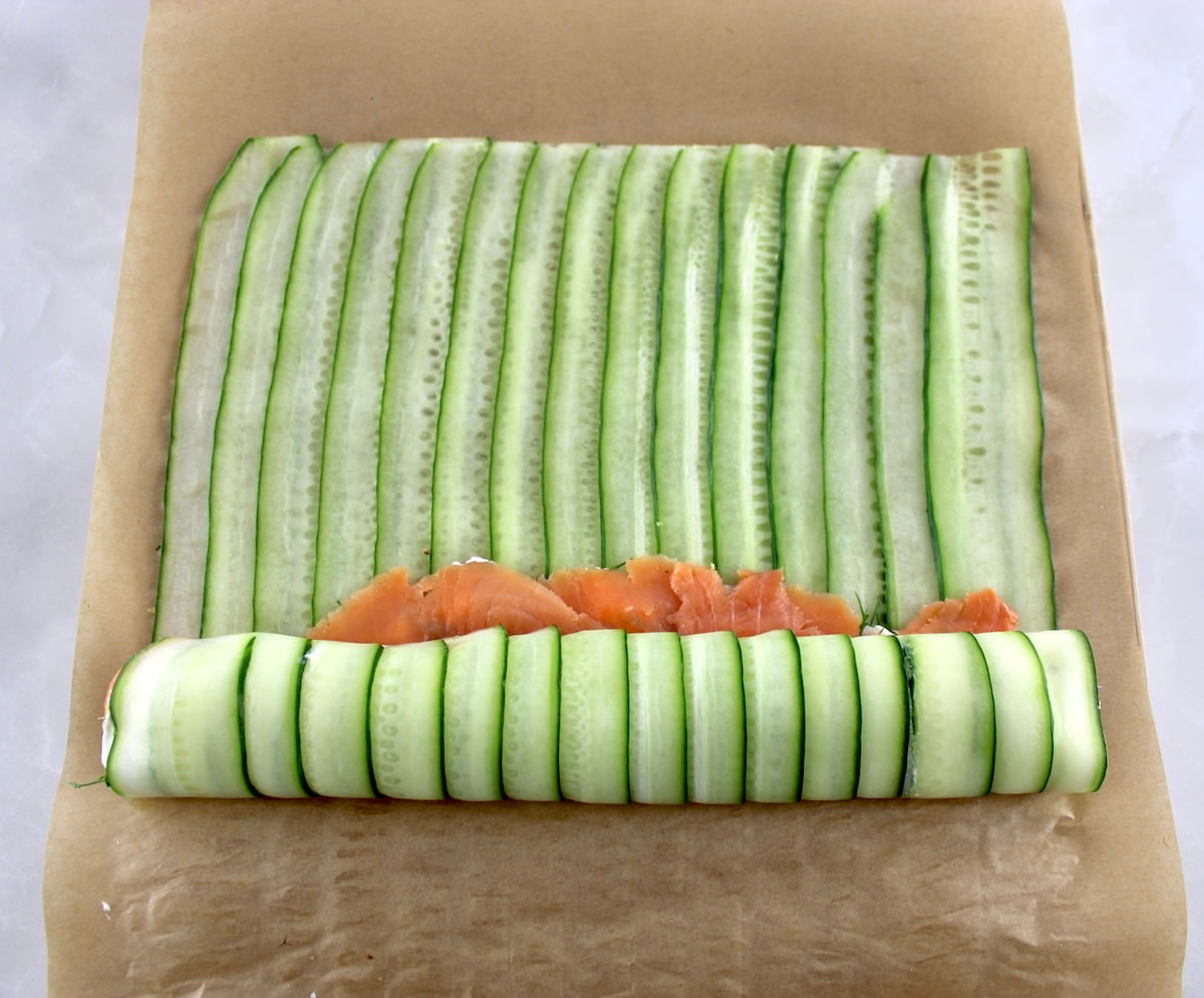 Salmon Cucumber Roll being rolled up on parchment