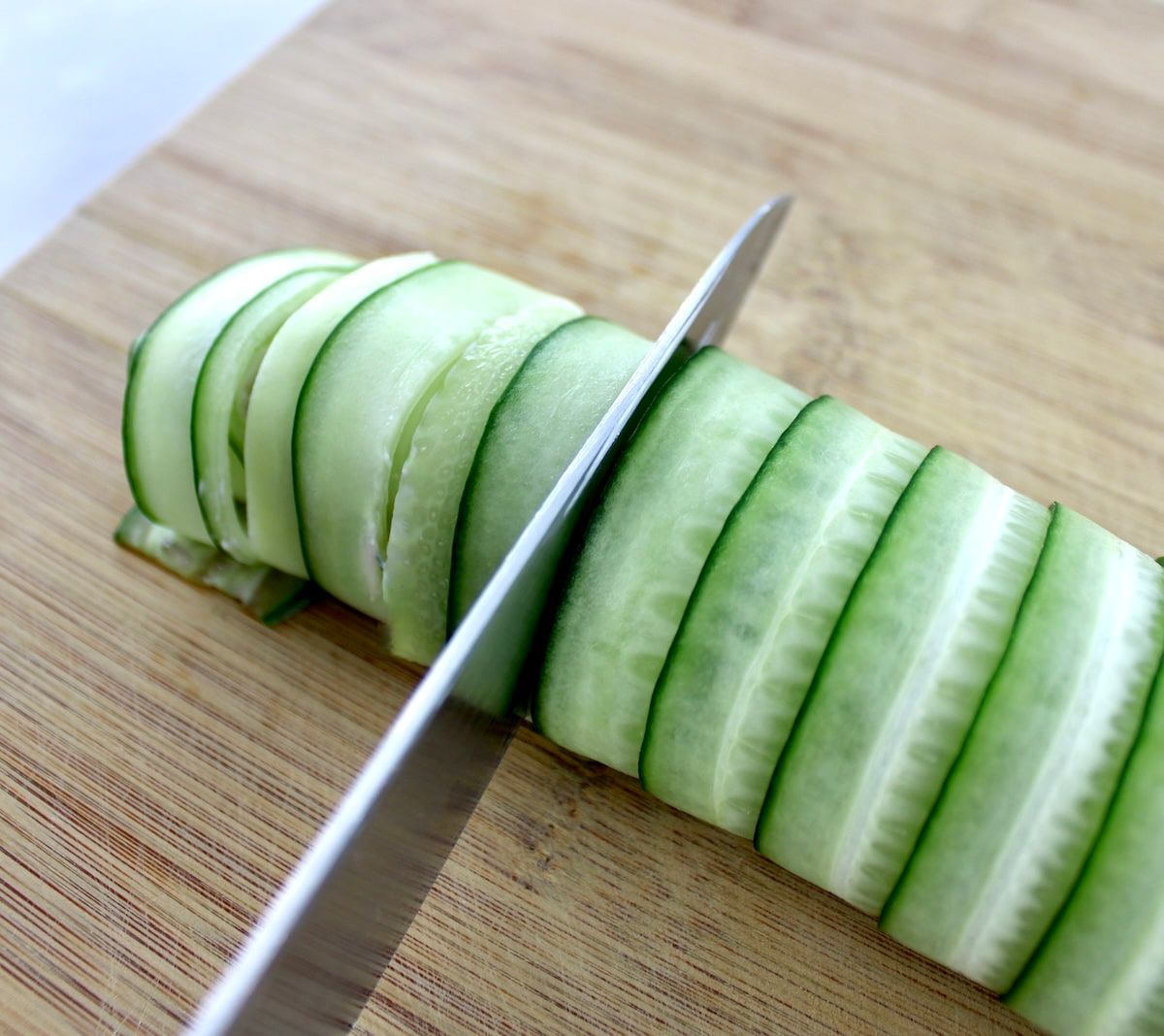 Salmon Cucumber Roll being cut into slices on cutting board