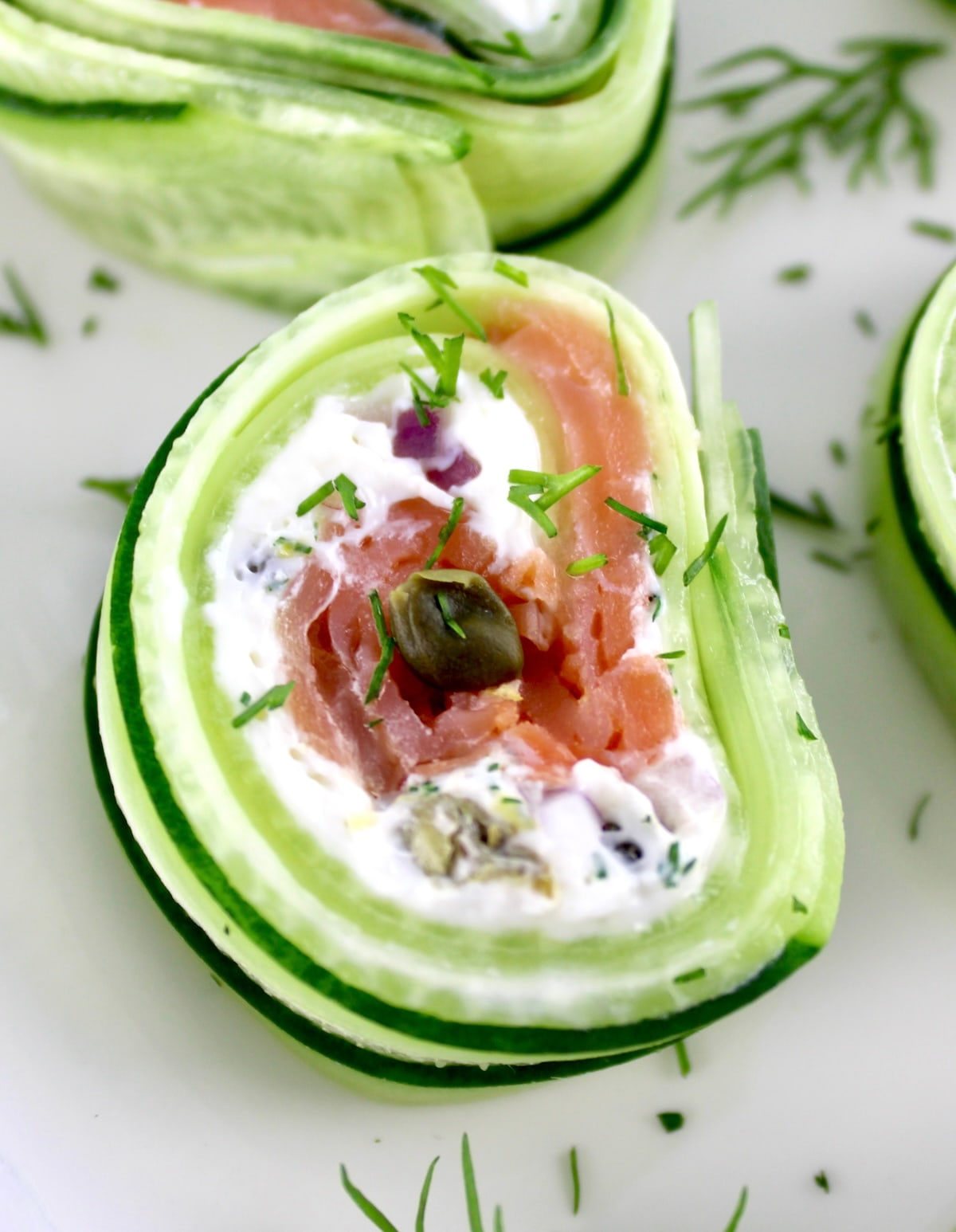 closeup of Salmon Cucumber Roll on white plate with fresh dill