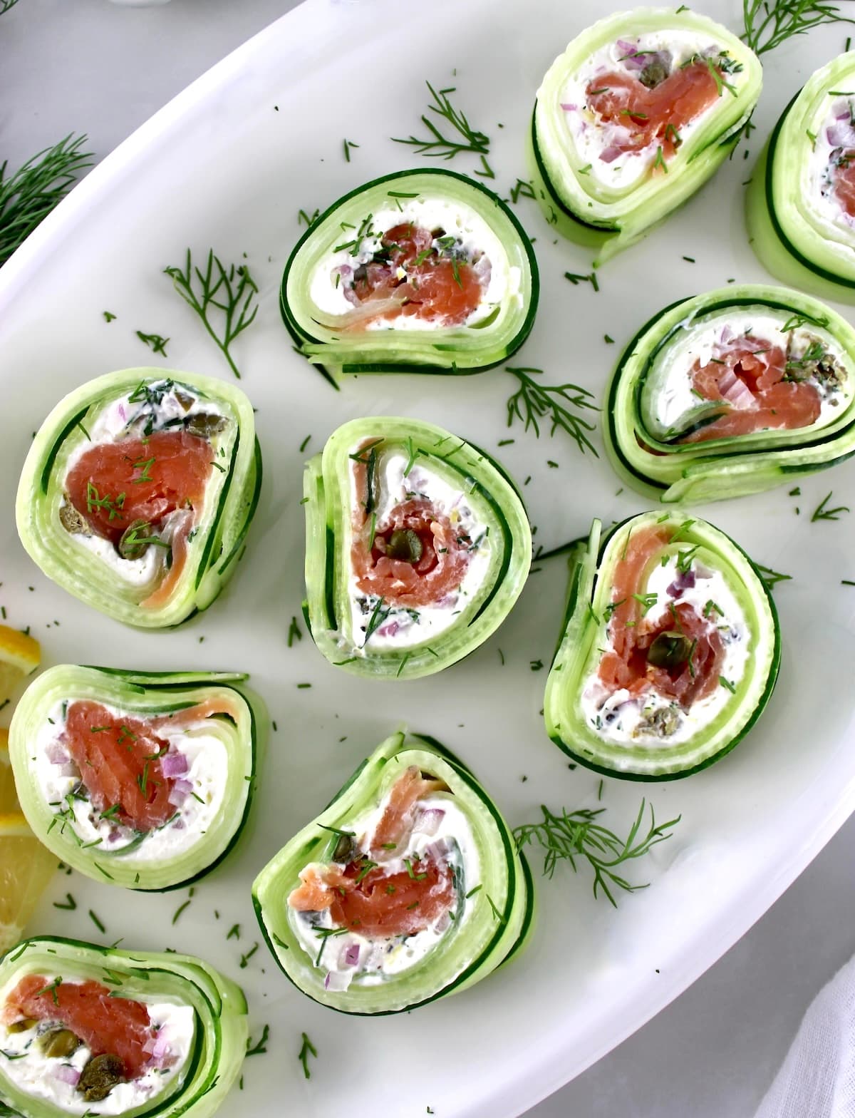 overhead view of Salmon Cucumber Rolls on white oval platter with fresh dill