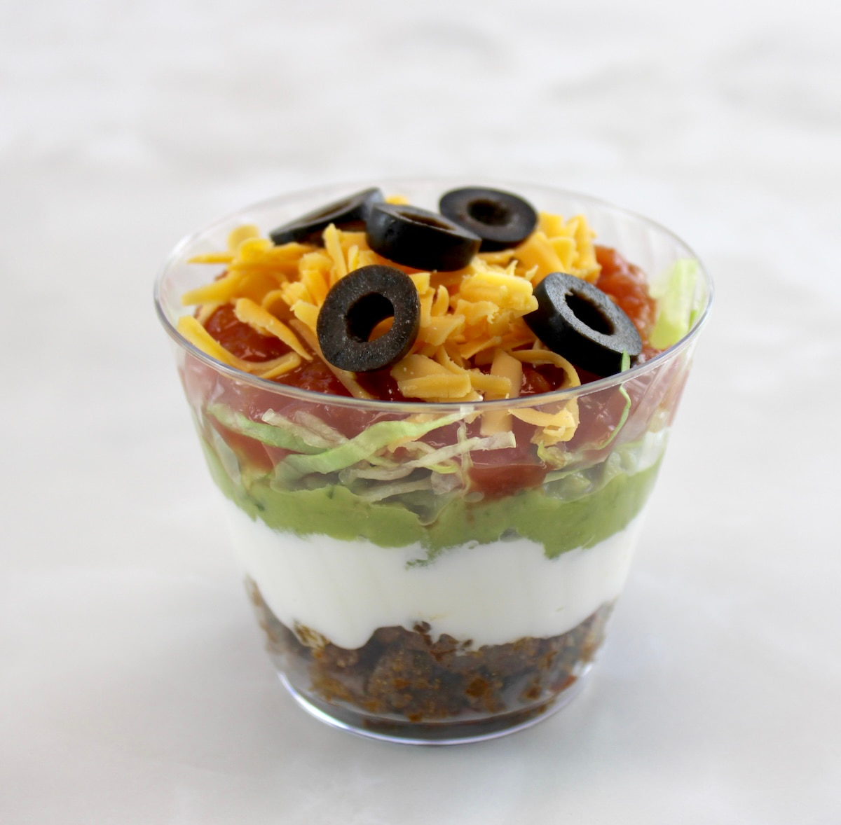 Taco Dip Cup with shredded cheese and sliced black olives on top