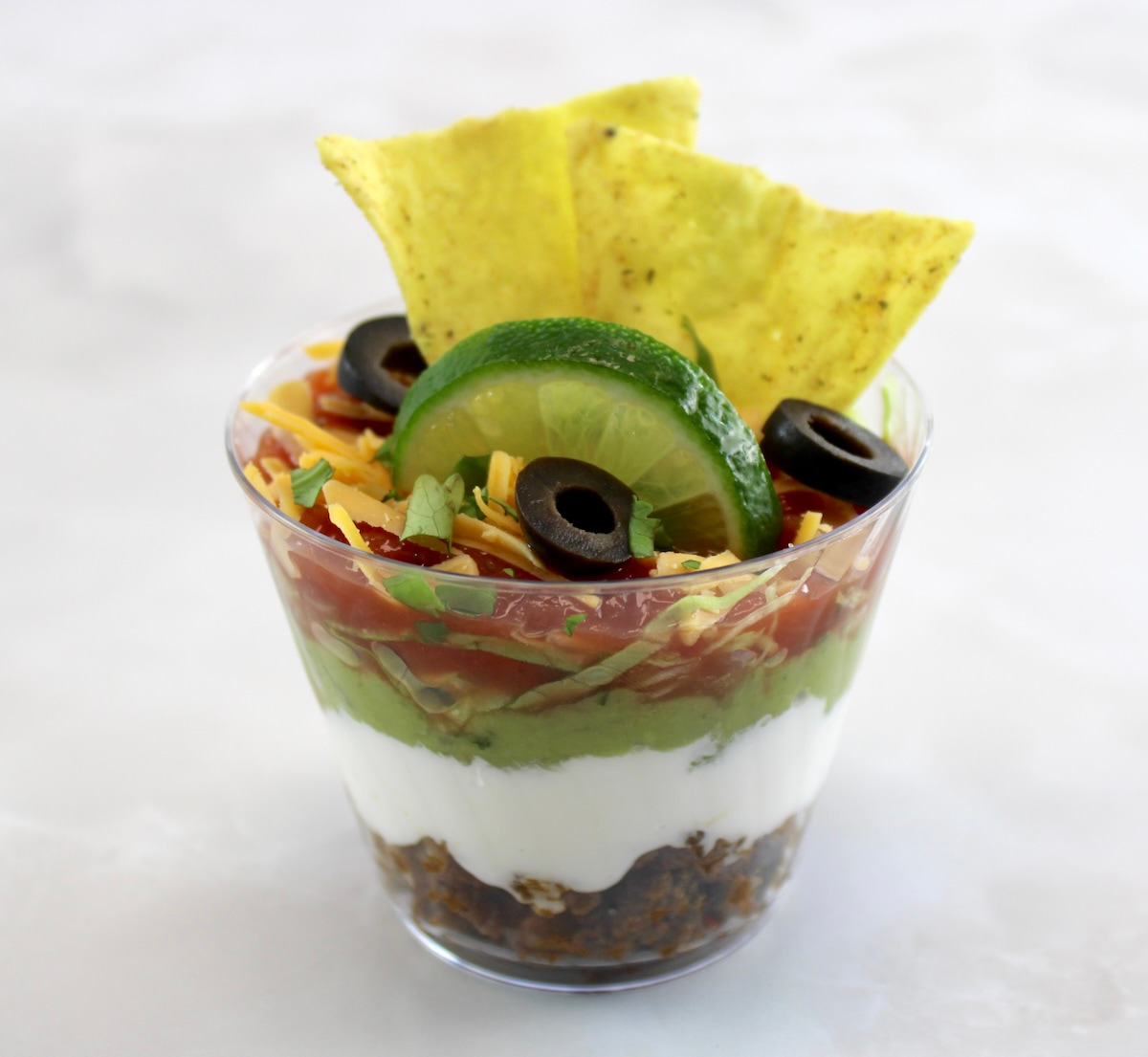 closeup side view of Taco Dip Cups with tortillas and lime slice on top