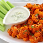 Air Fryer Buffalo Cauliflower on white plate with celery and blue cheese