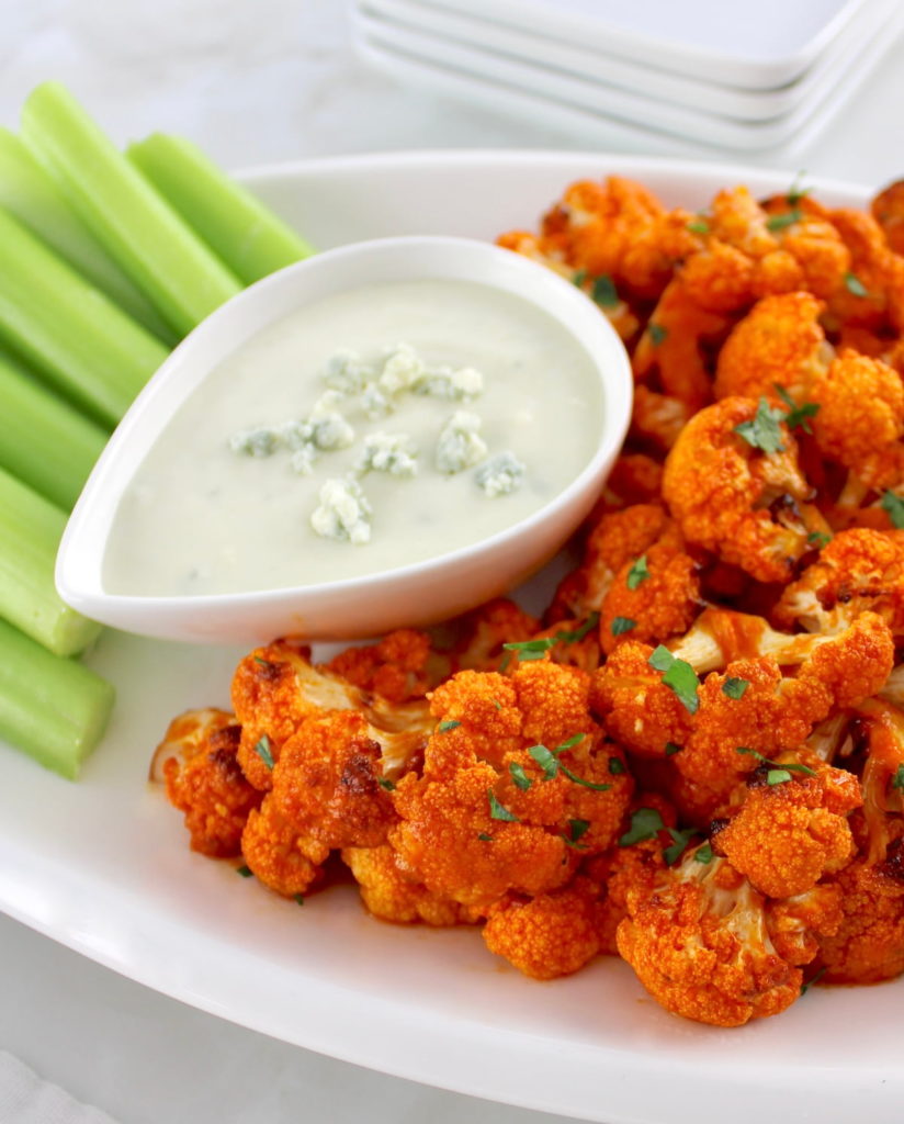 Air Fryer Buffalo Cauliflower on white plate with celery and blue cheese