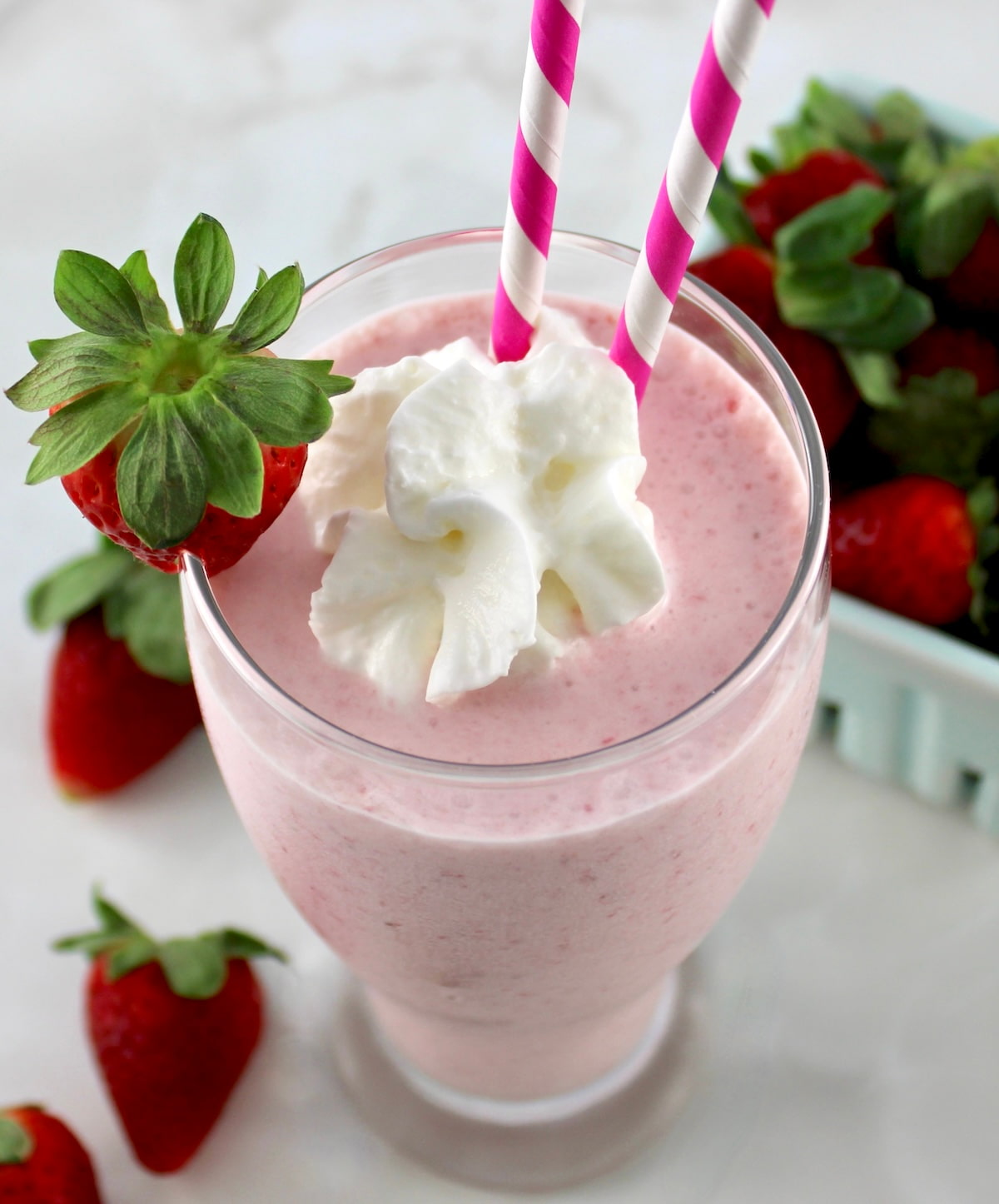 overhead view of Keto Strawberry Milkshake in glass with whip cream and 2 straws
