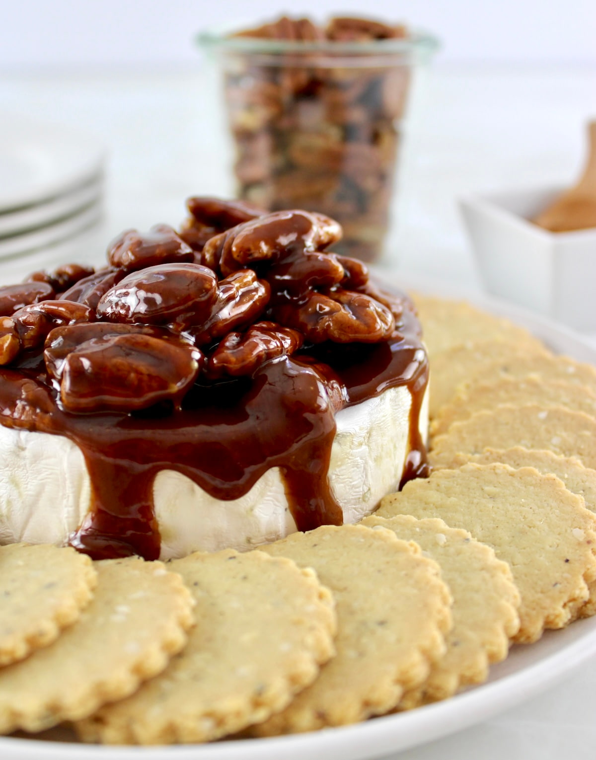 closeup of Maple Pecan Baked Brie on white plate with crackers around