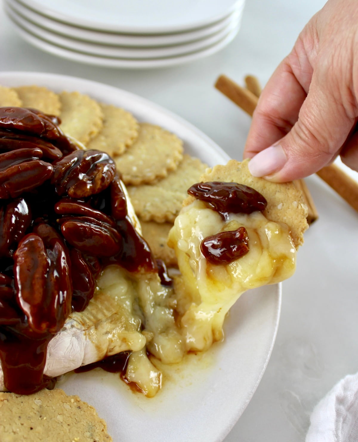 Maple Pecan Baked Brie on cracker with cheese pulling