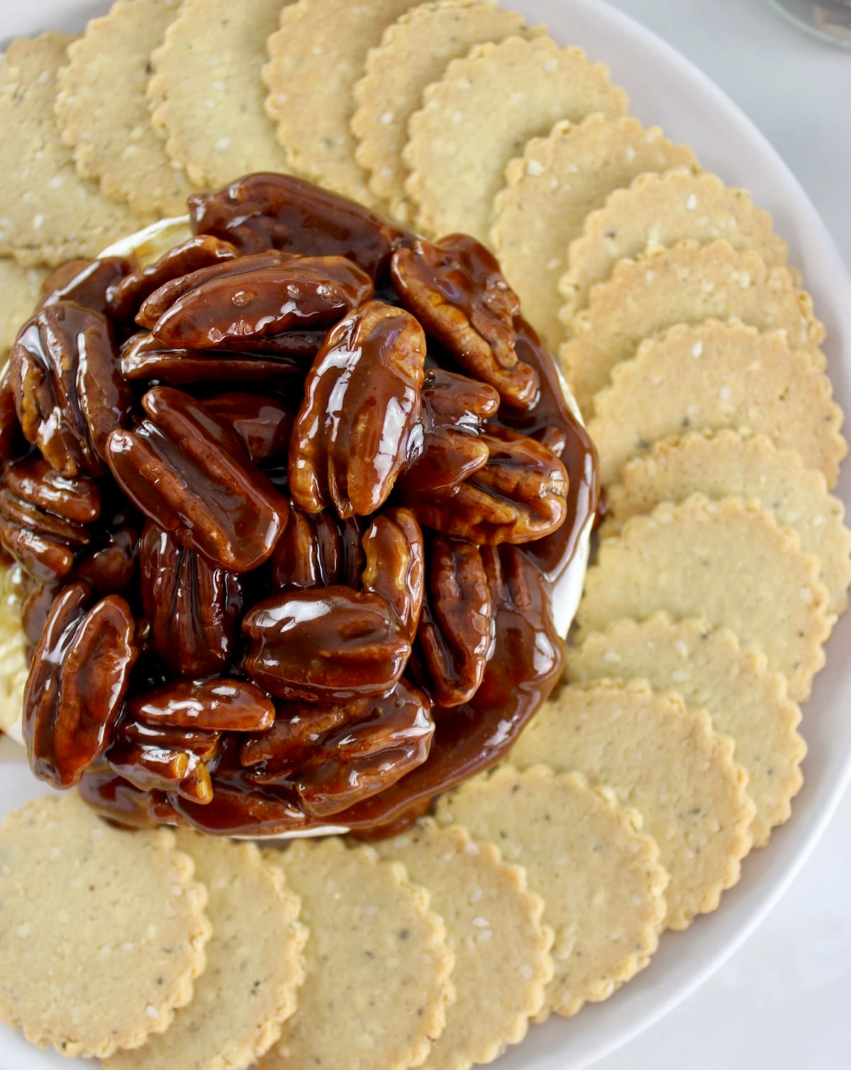 overhead view of Maple Pecan Baked Brie with crackers around on white plate