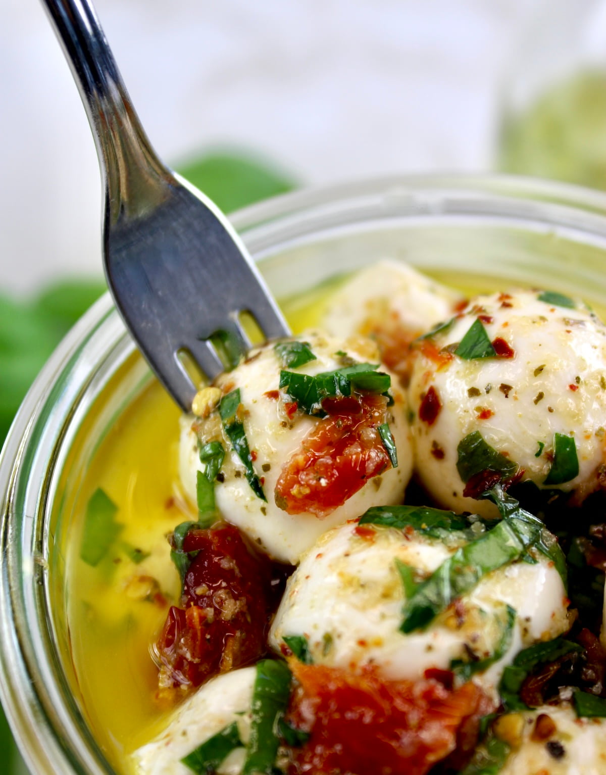 Marinated Mozzarella Balls (Ciliegine) in glass jar with fork pulling one out