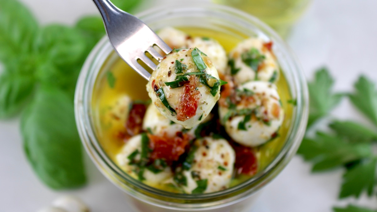 Marinated Mozzarella Balls (Ciliegine) in glass jar with fork pulling one out