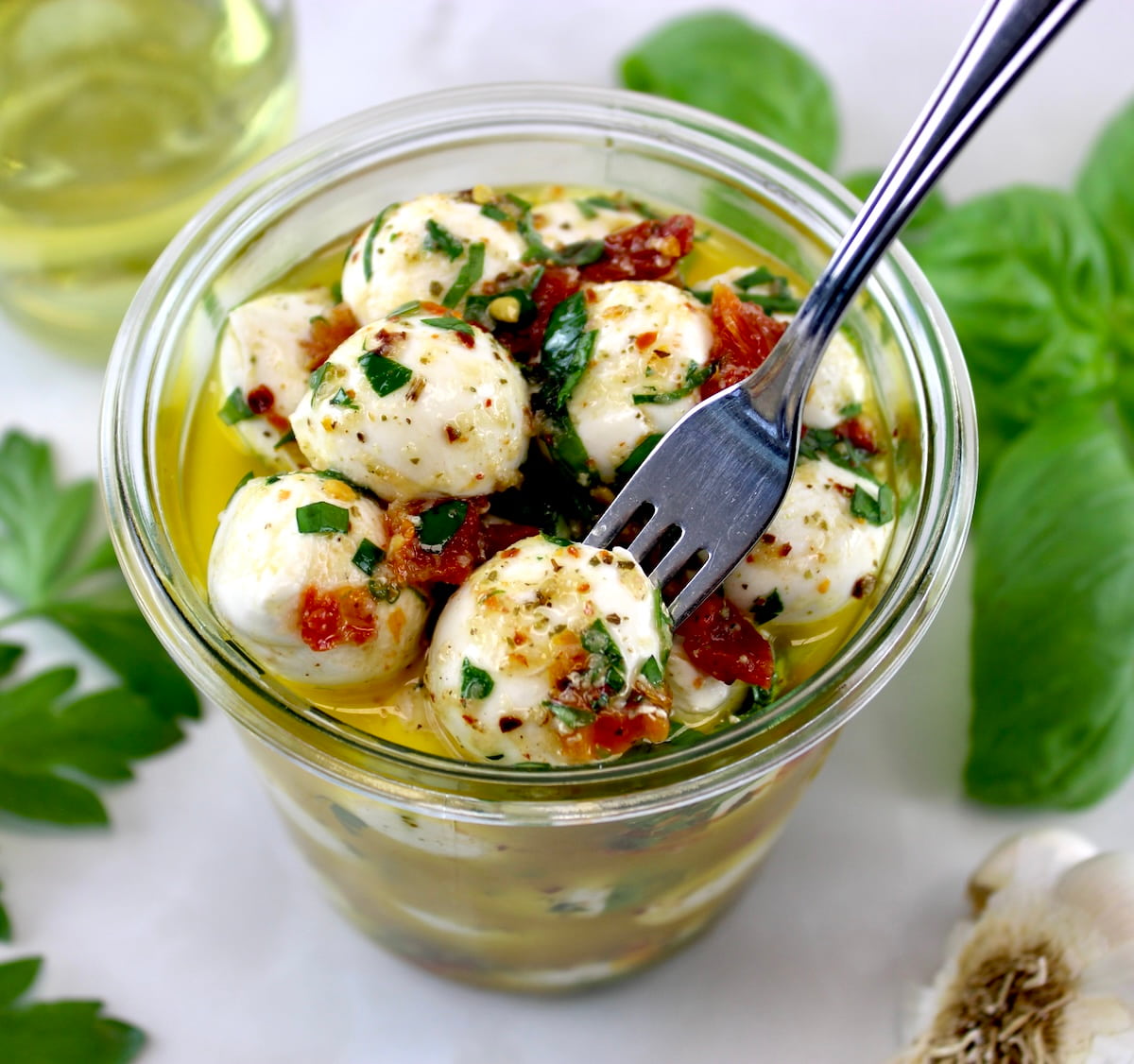 Marinated Mozzarella Balls (Ciliegine) in glass jar with fork pulling one out