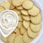 Sesame Almond Flour Crackers on plate in concentric circles around a dip in white bowl