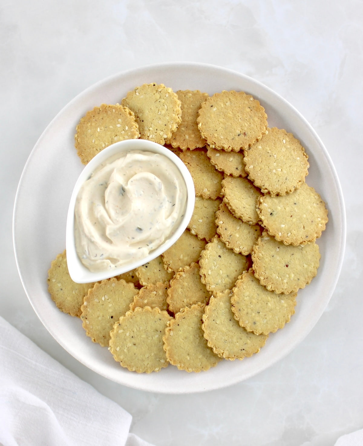 overhead view of Sesame Almond Flour Crackers on white plate with dip