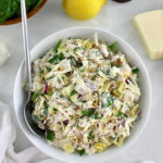 Spinach Artichoke Chicken Salad in white bowl with spoon on side