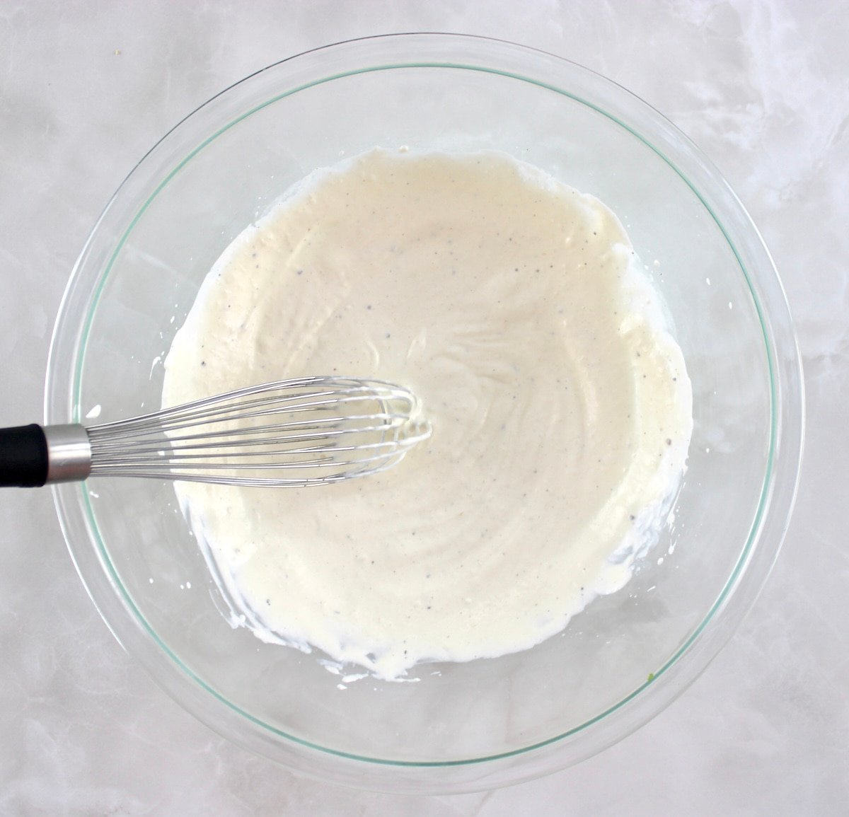 Spinach Artichoke Chicken Salad dressing in glass bowl with whisk