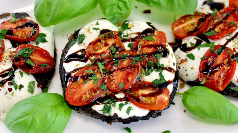 closeup of Caprese Stuffed Portobellos on white plate with balsamic drizzle and fresh basil