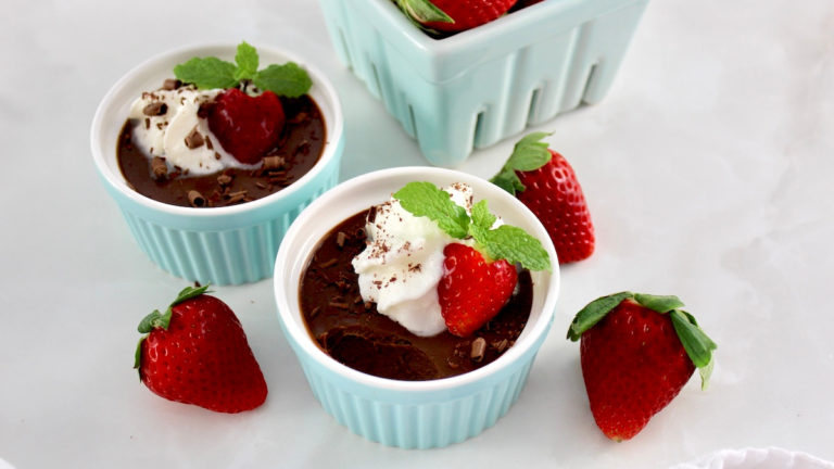 overhead view of Chocolate Pots de Crème in blue ramekin with whip cream and strawberry on top