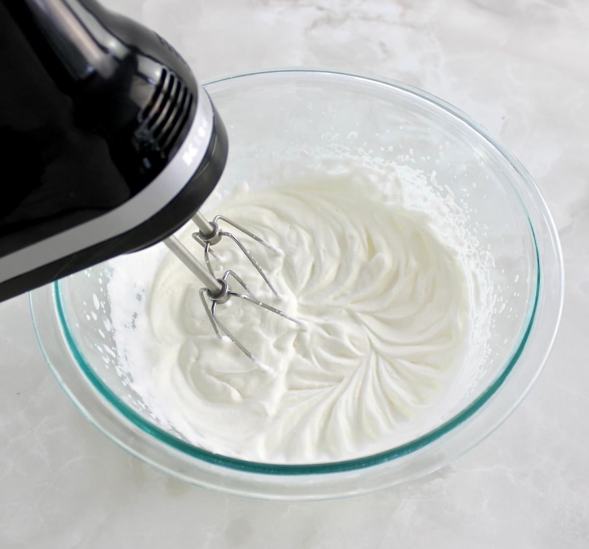 whip cream in glass bowl with hand mixer