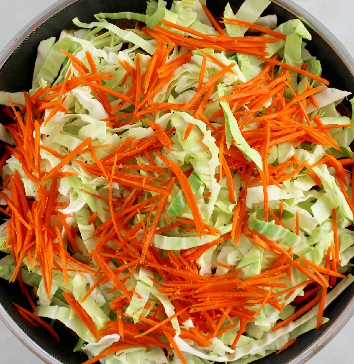 shredded raw carrots and cabbage in skillet