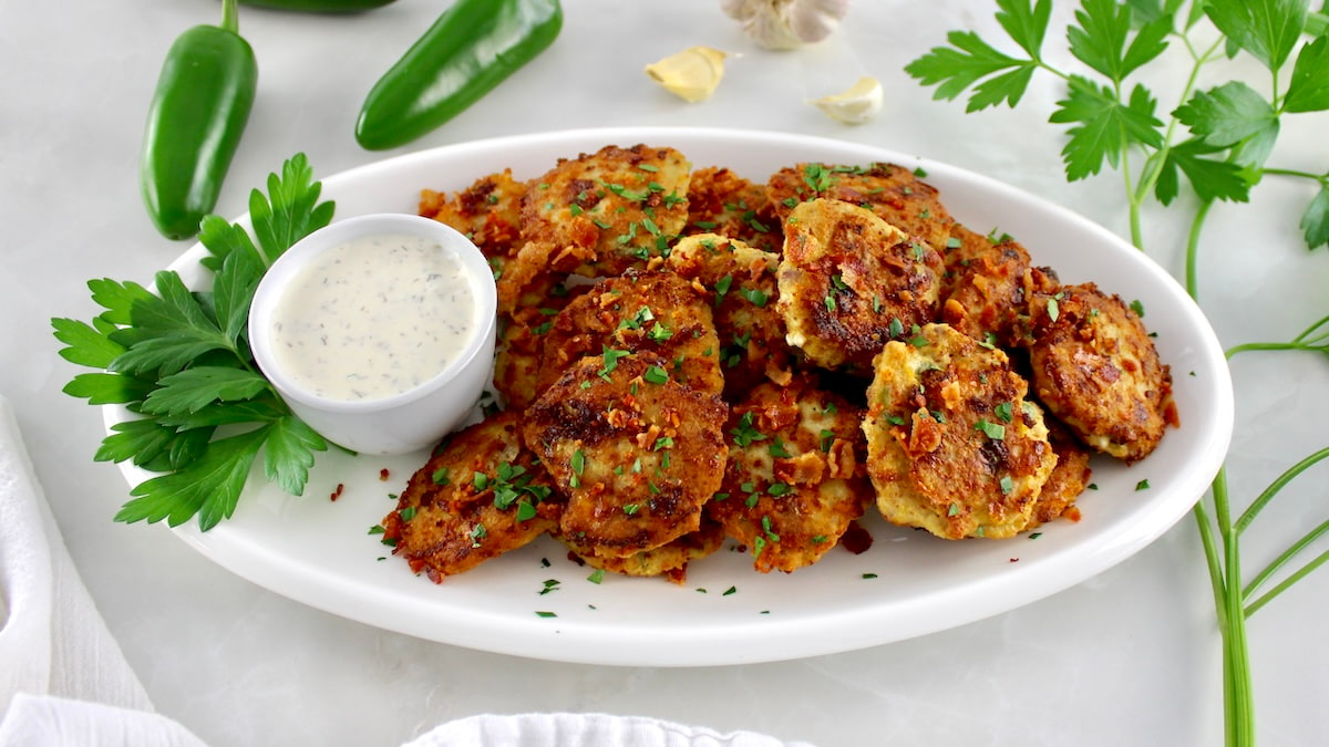 Jalapeño Popper Chicken Fritters on oval platter with ranch drip on side with parsley garnish