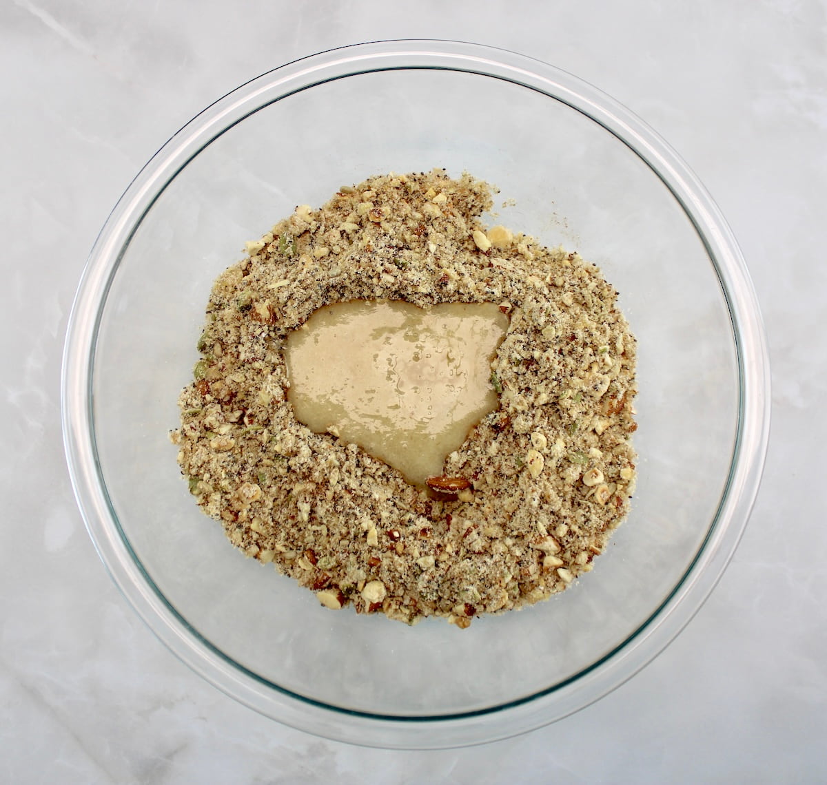 Keto Granola with melted coconut oil in glass bowl
