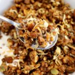 Keto Granola in spoon with milk held up over bowl