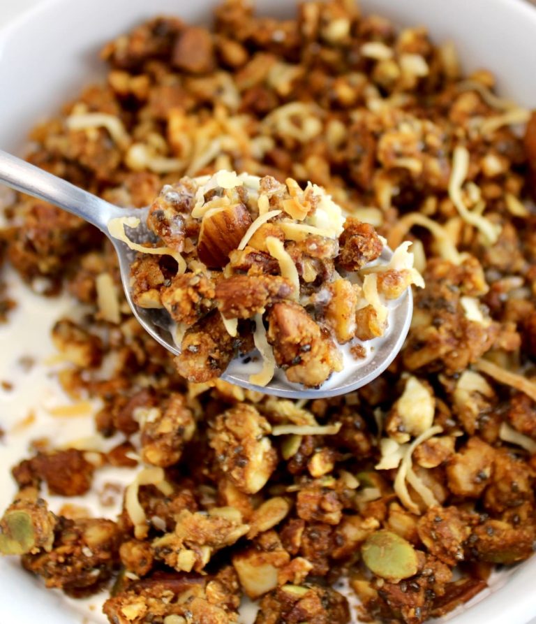 Keto Granola in spoon with milk held up over bowl